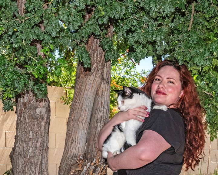 Sonora under a tree holding her cat